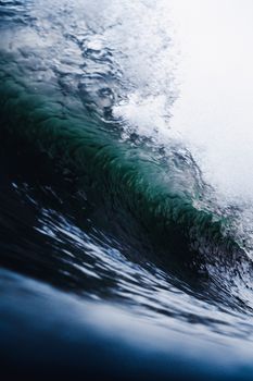 From below of shiny powerful wave of stormy turquoise ocean with transparent water under cloudy sky