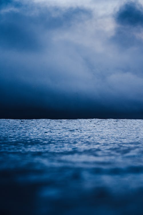 Calm water of rippling sea under cloudy sky