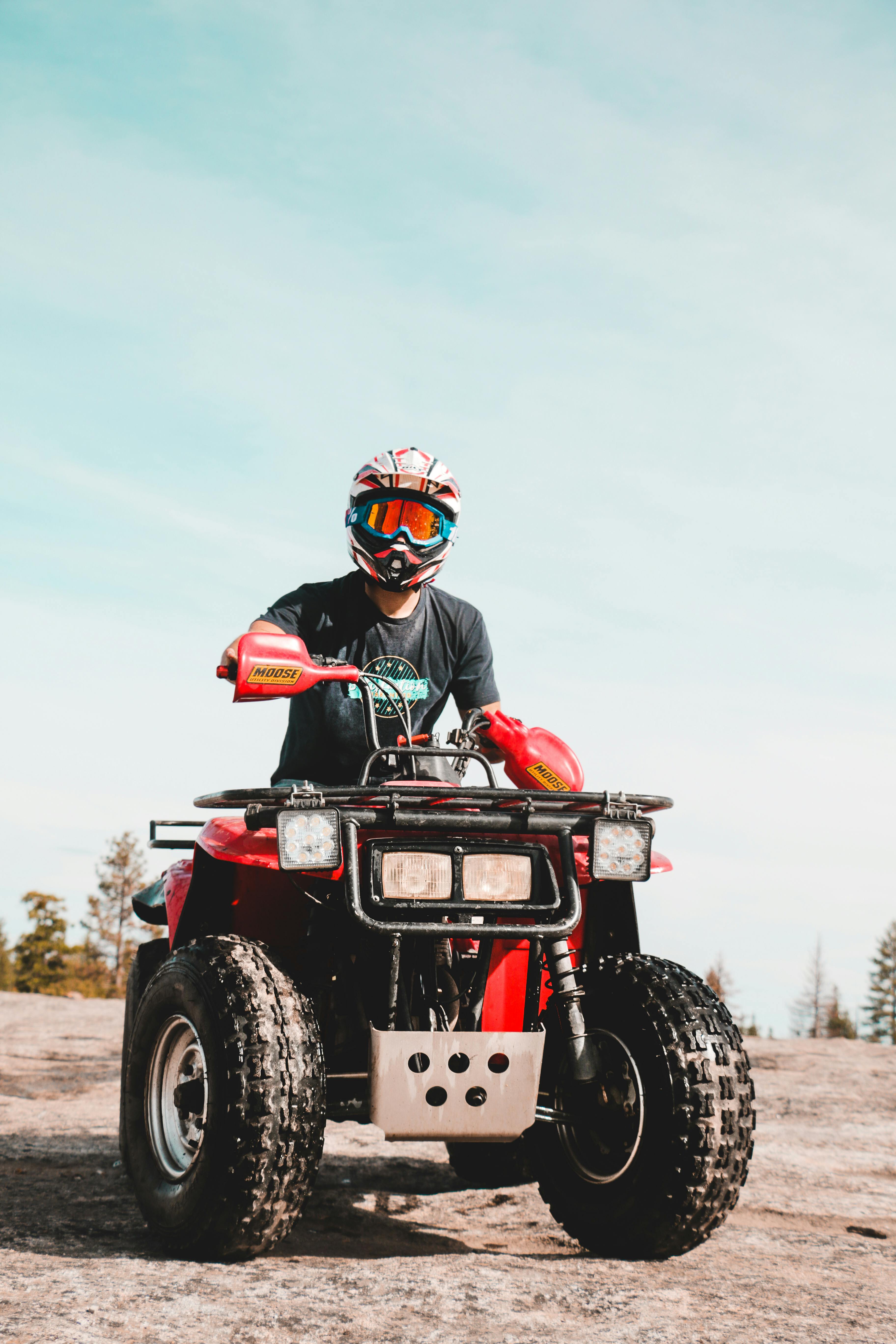 A man enjoys a ride on a quad bike outdoors on a sunny day, wearing a helmet and goggles.