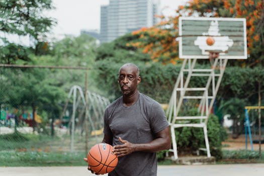 A man with a basketball on an outdoor court in a city park.