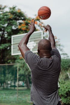 Adult man shooting a basketball on an outdoor court, showcasing focus and skill.