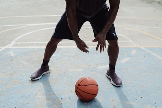 An athletic man in action on an outdoor basketball court, ready for a play.