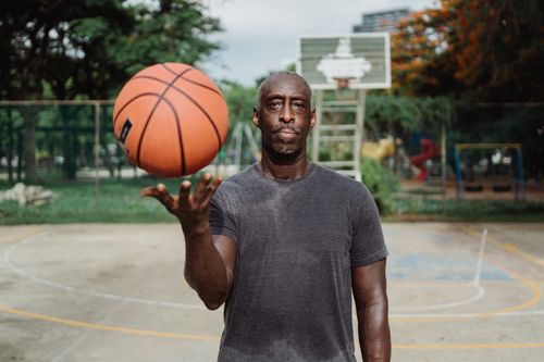 Free Man spinning a basketball on an outdoor court, showcasing focus and skill. Stock Photo