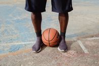 Person in Black Shorts and Black Flip Flops Holding Basketball