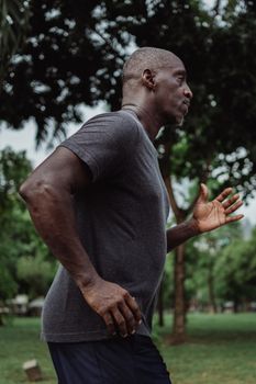 Side view of a focused man running in a lush green park, embodying a healthy lifestyle.