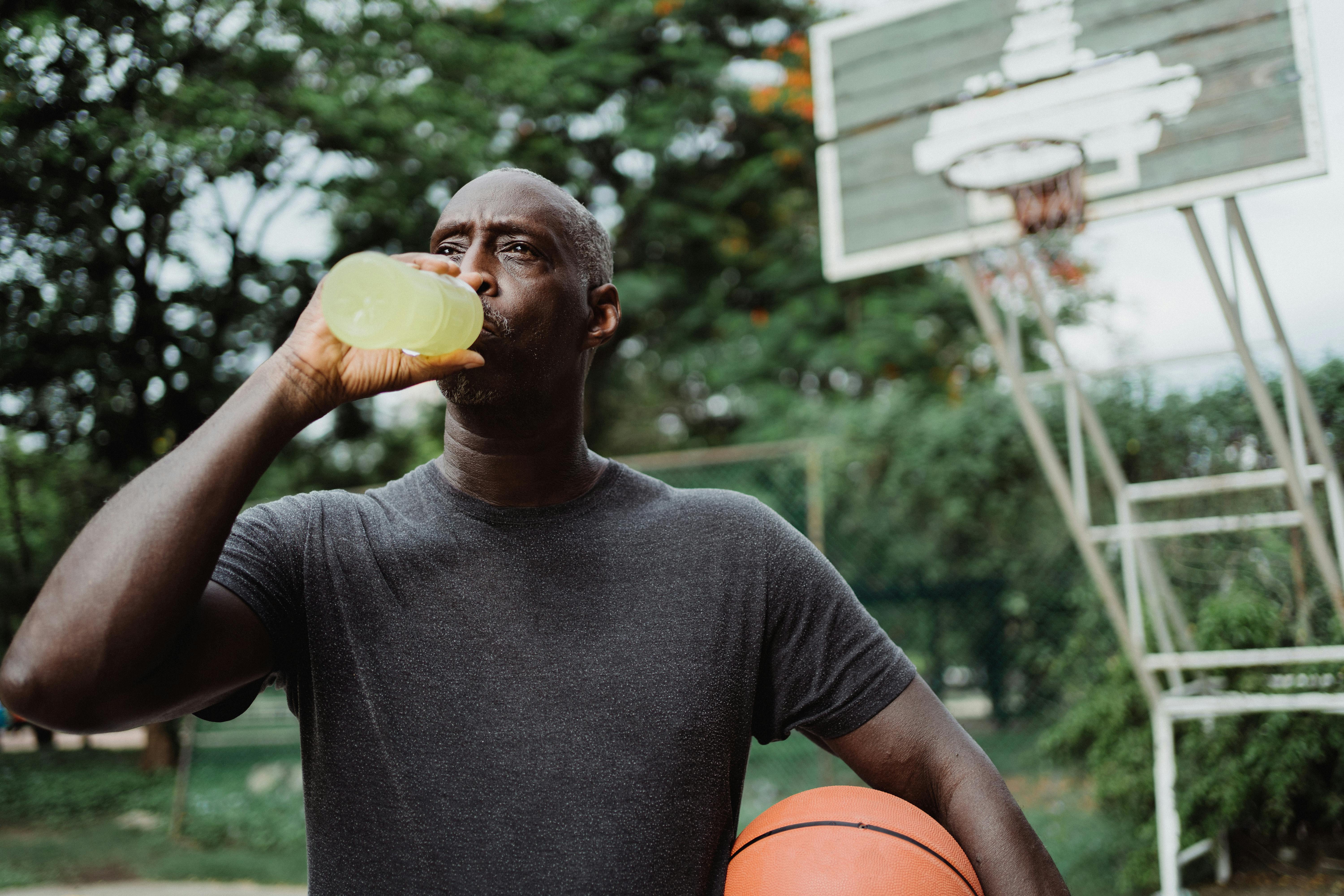 man in black crew neck t shirt drinking yellow liquid from plastic bottle