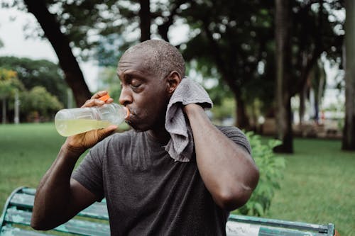 Free Man in Black Crew Neck T-shirt Drinking Yellow Liquid from Plastic Bottle Stock Photo