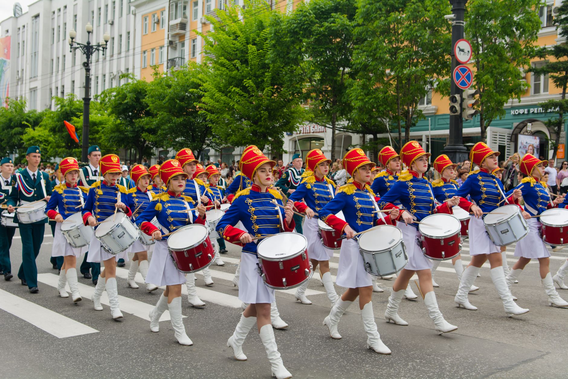 Colorful marching band performing in a lively urban parade, showcasing drummers in traditional uniforms.