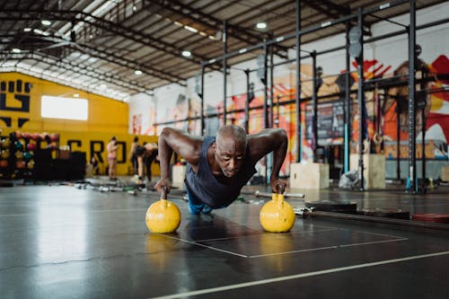 Photo of Man Doing Push-Ups Using Yellow Kettlebell