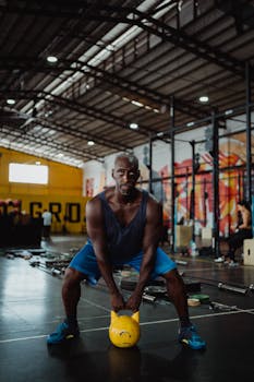 Determined man performing kettlebell exercise indoors, showcasing fitness and strength.