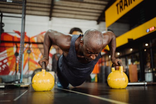 A determined man performs push-ups on kettlebells in a gym, emphasizing strength and fitness.