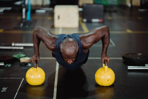 Photo of Man Doing Push-Ups Using Yellow Kettlebell