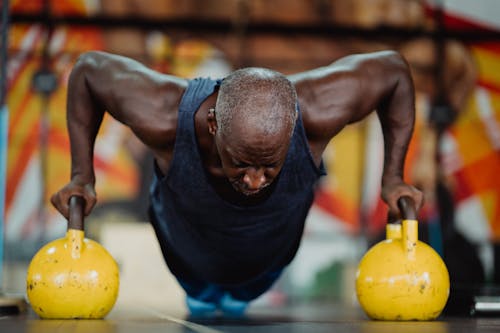 Photo of Man Doing Push-Ups Using Yellow Kettlebell