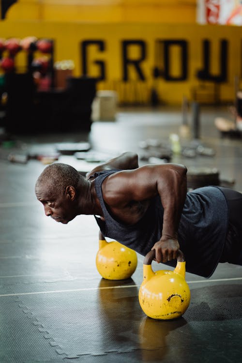 Photo of Man Doing Push-Ups Using Yellow Kettlebell