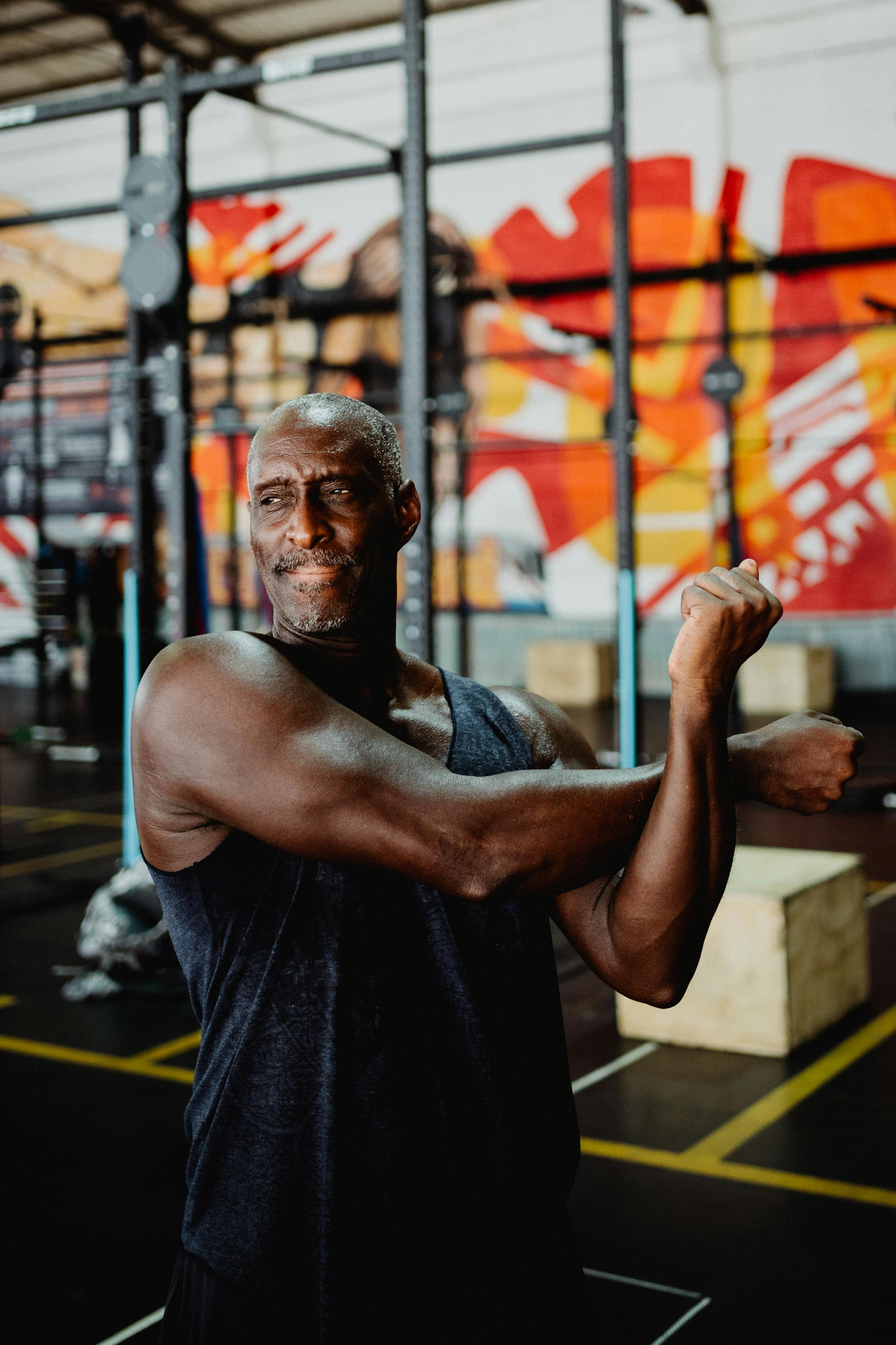 Black man in activewear stretching in a colorful urban gym setting.