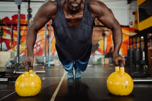 Photo of Man Doing Push-Ups Using Yellow Kettlebell