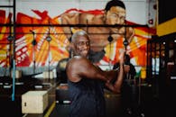 这张照片令人印象深刻，一位健硕的黑人长者正在充满活力的室内健身房中展示身体