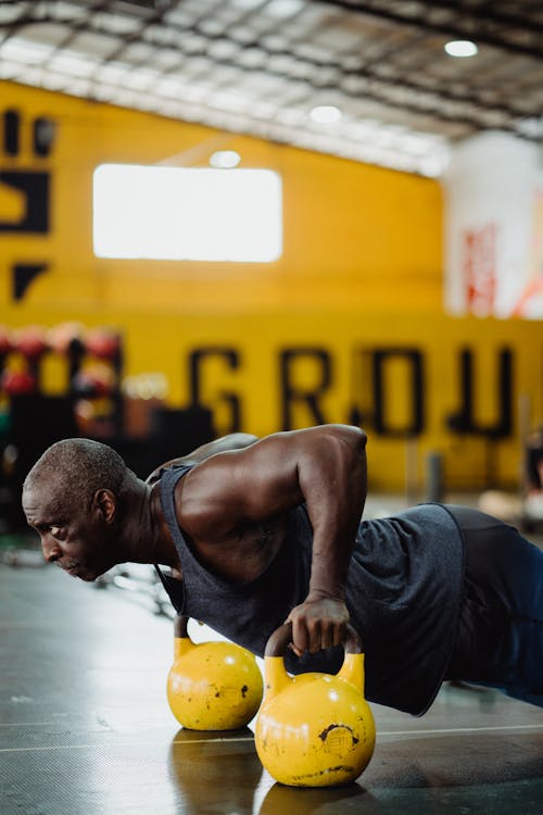 Photo of Man Doing Push-Ups Using Yellow Kettlebell