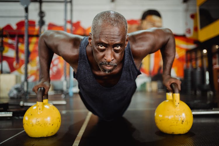 Photo Of Man Doing Push-Ups Using Yellow Kettlebell