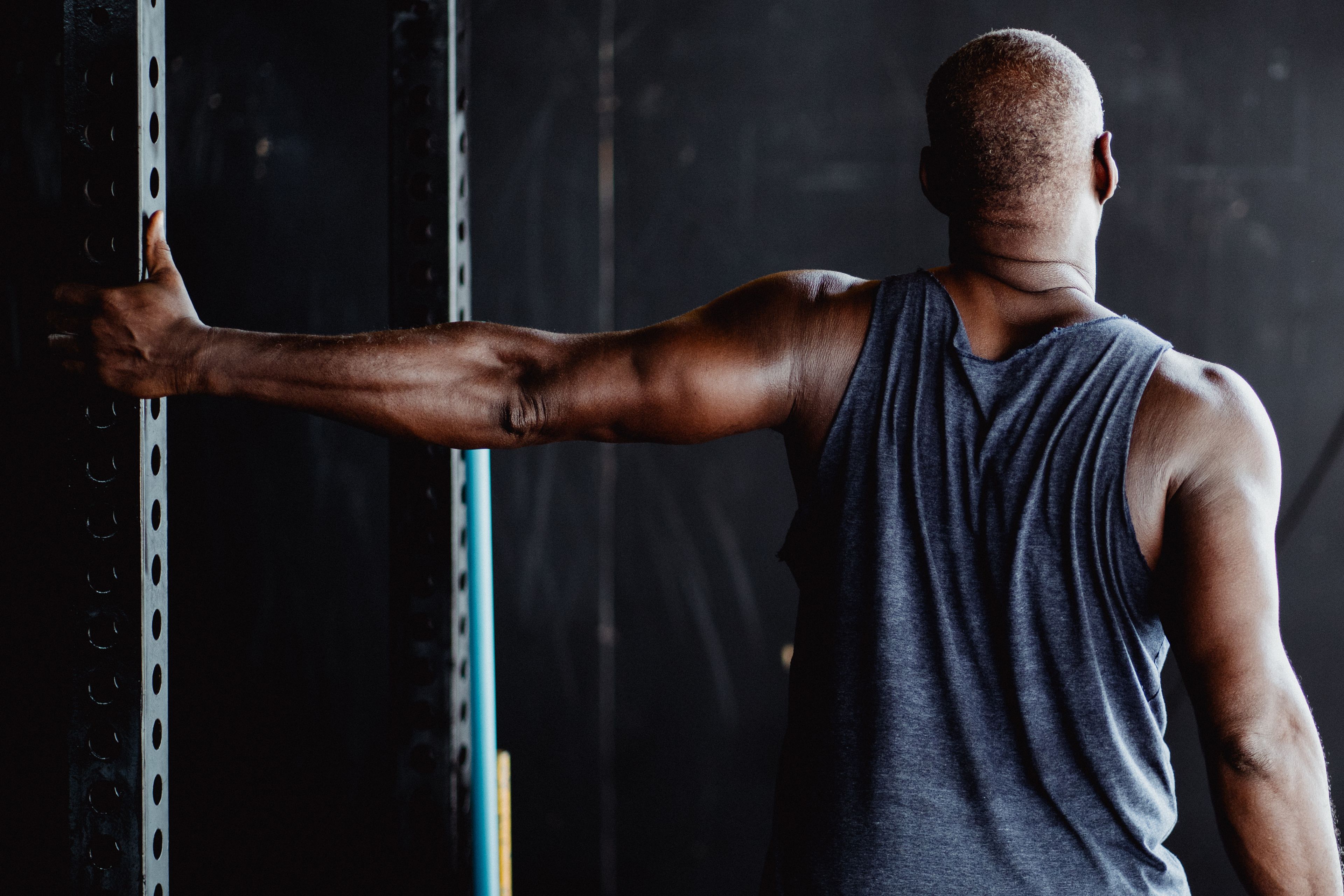 An athletic man stretching his arm in a gym, showcasing strength and flexibility.