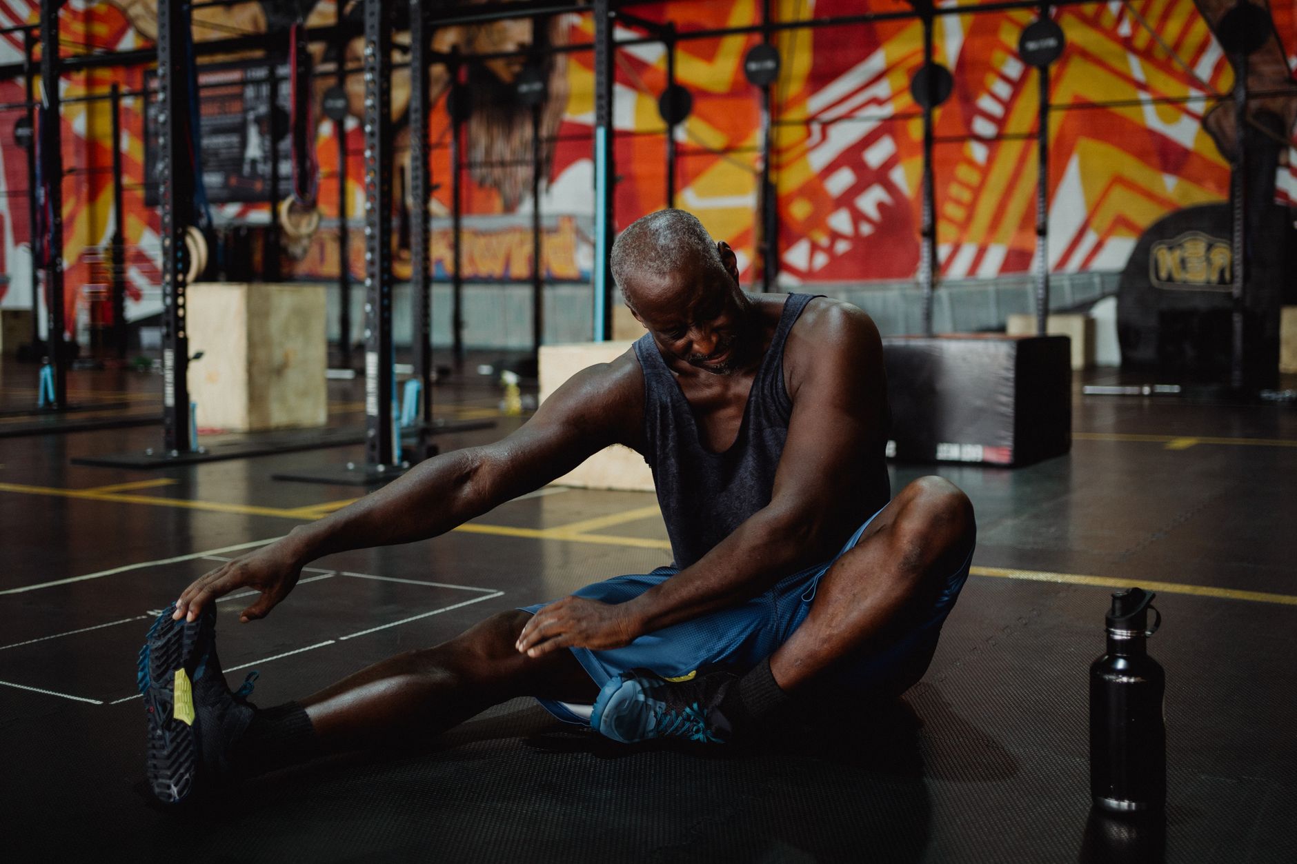 Senior adult man stretching in a vibrant gym setting, promoting fitness and wellness.