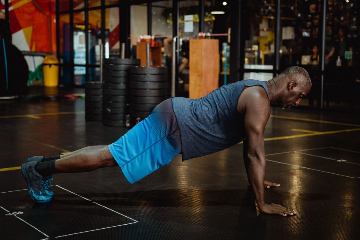 Man doing push-ups on a gym floor during a bodyweight circuit workout