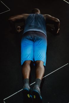 A focused athlete doing push-ups on a gym floor, showcasing determination and strength.