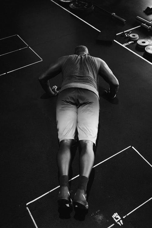 Grayscale Photo of Man in Blue Shorts Doing Push-Ups