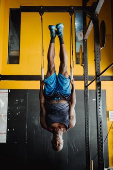 Athlete performs an inverted exercise on gymnastic rings in a vibrant indoor gym.