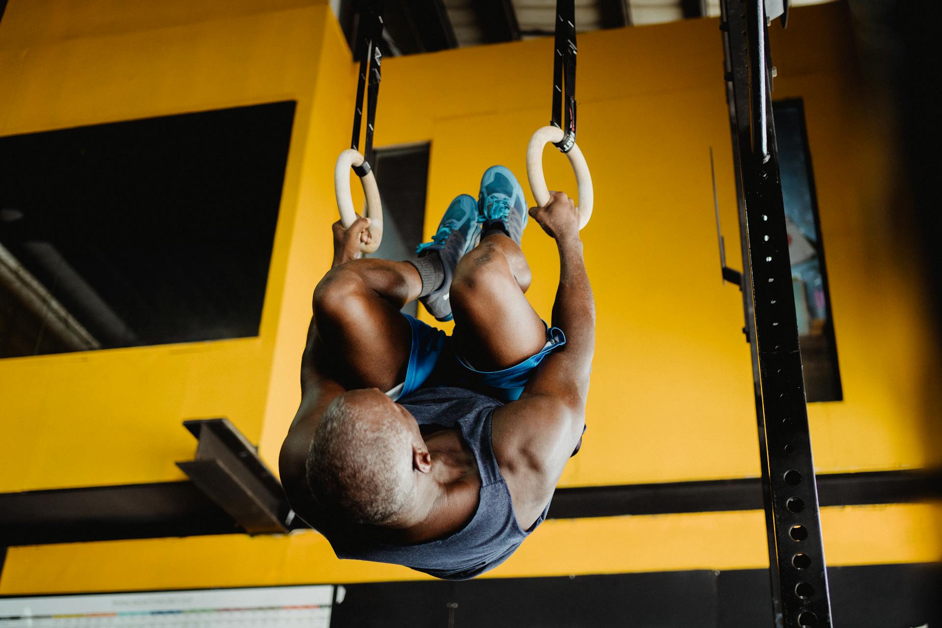 Man Hanging on Hoops Upside Down on a Gym