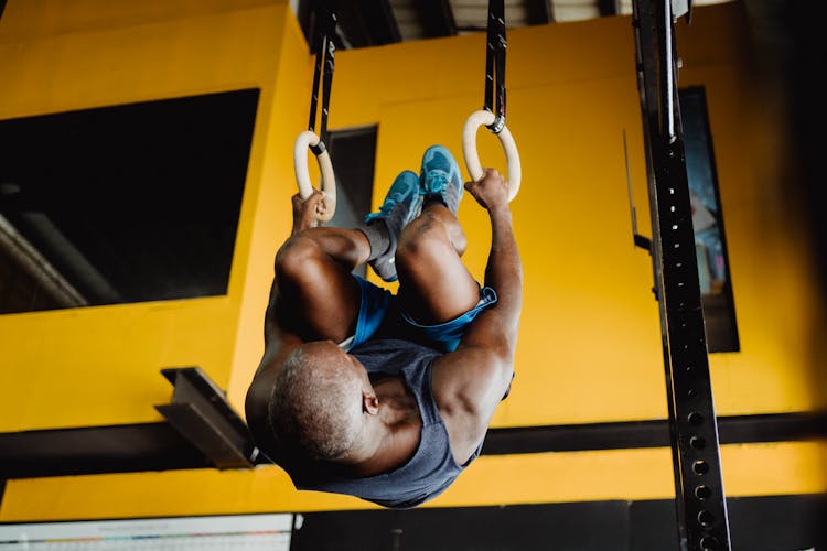 Man Hanging On Hoops Upside Down On A Gym 