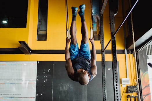 Man performing gymnastics on rings indoors, showcasing strength and fitness.