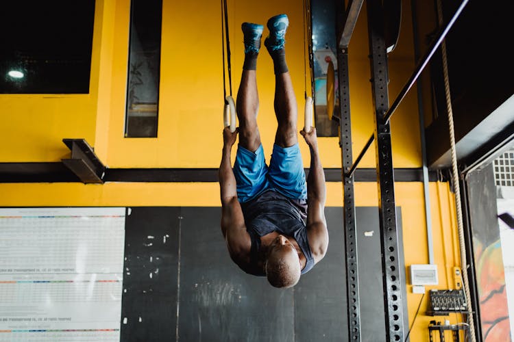 Man Hanging On Hoops Upside Down On A Gym 