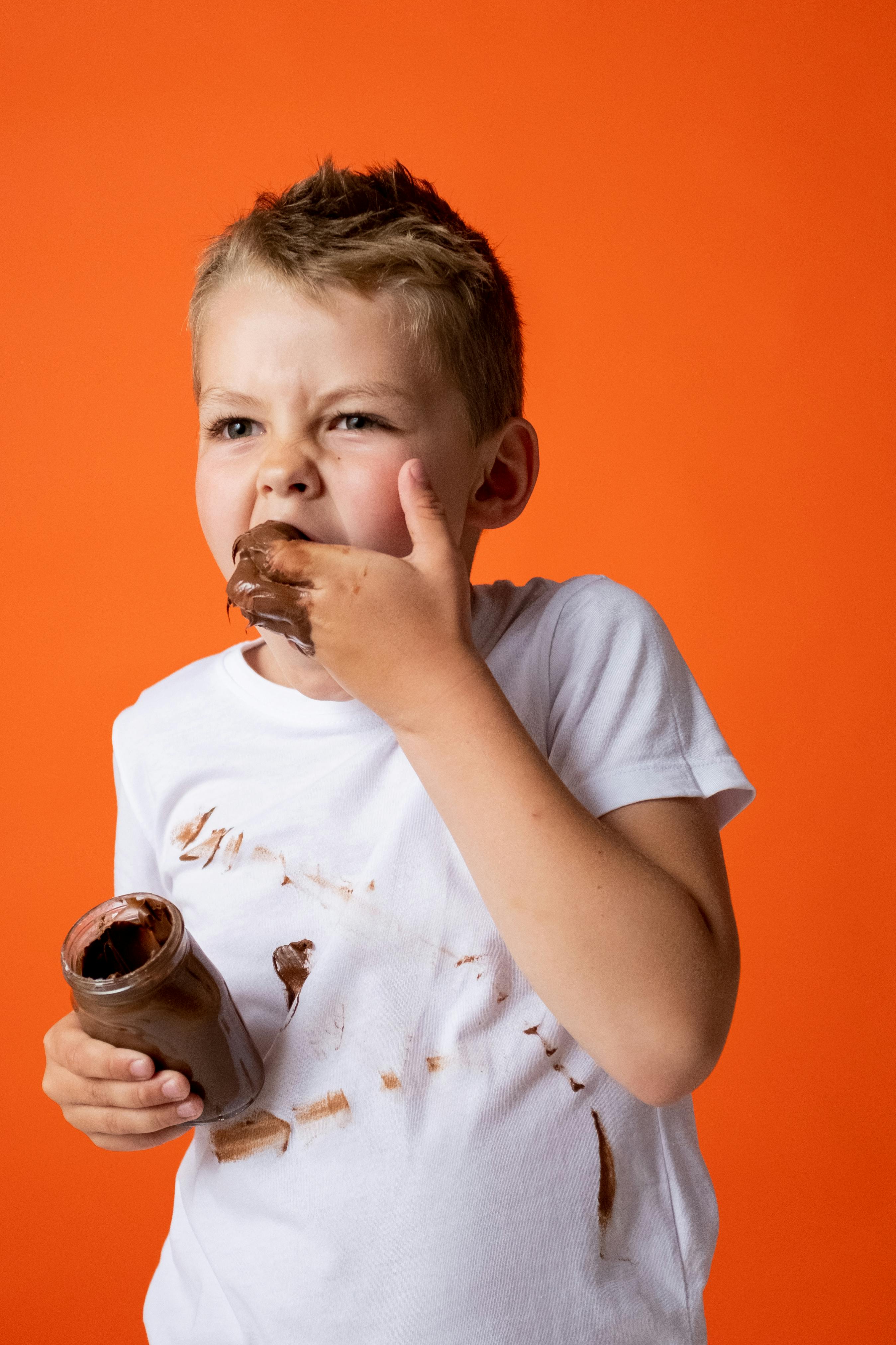 Boy in White Crew Neck T-shirt Holding Chocolate Jar