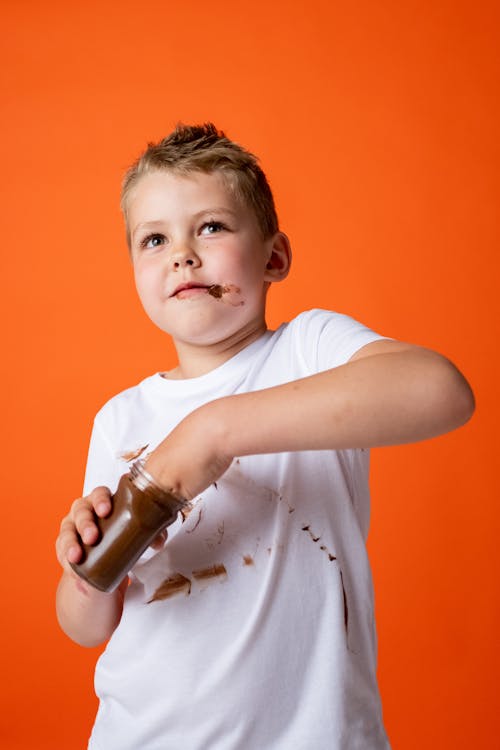 Boy in White Crew Neck T-shirt Holding Chocolate Jar