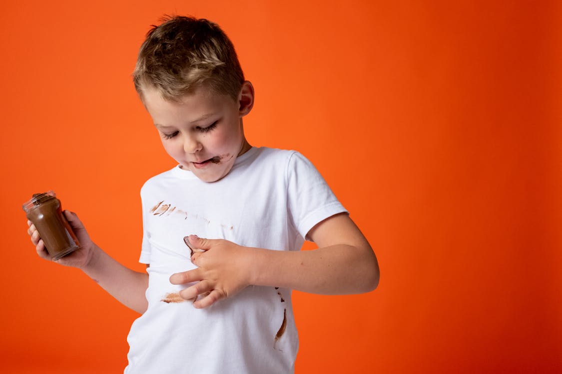 Boy in White Crew Neck T-shirt Holding Chocolate Jar