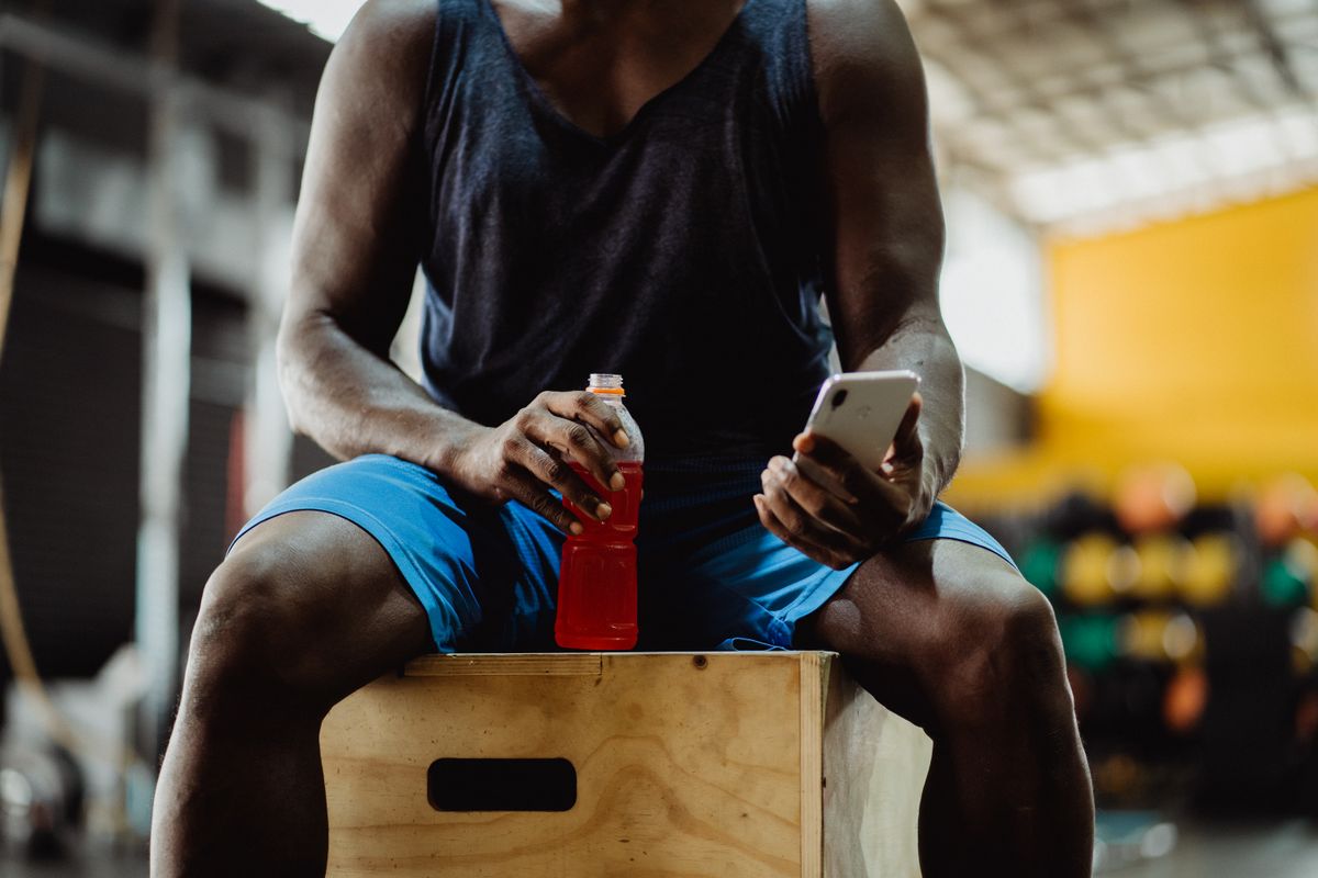 Athlete seated in a gym while using a smartphone