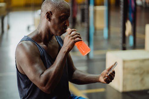 Man in Tank Top Drinking from Plastic Bottle