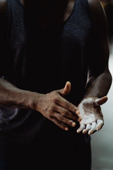 A focused athlete prepares with chalked hands indoors, highlighting dedication and strength.