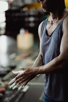 African American man clapping hands with chalk in gym, ready for exercise