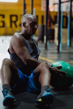 Adult man working out with a medicine ball in an industrial-style gym setting.