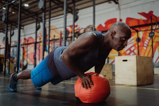 Man working out in gym, performing push-up on exercise ball for core strength.