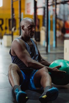 A focused man doing core exercises with a medicine ball indoors, enhancing fitness.