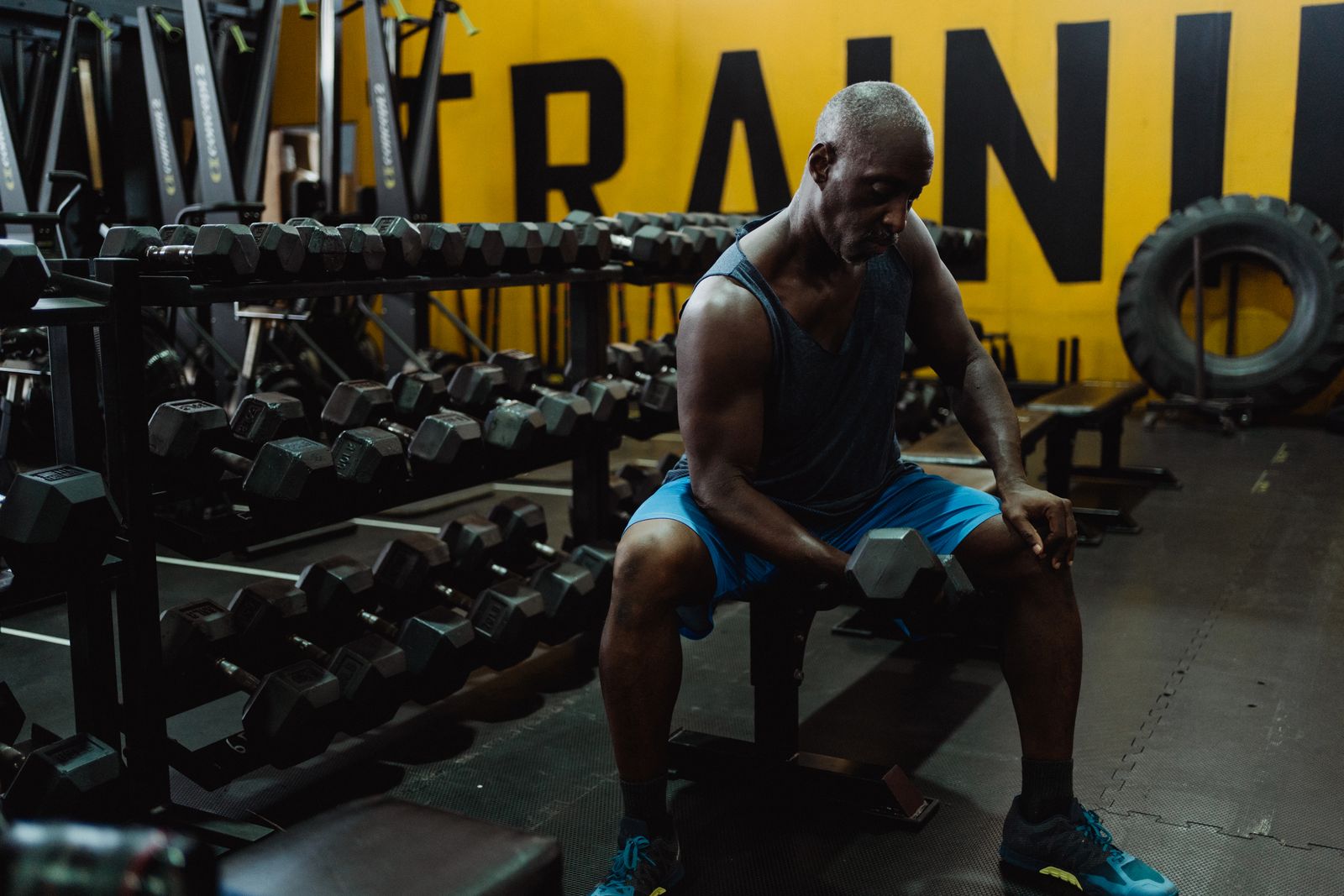 Middle-aged man strength training with dumbbells in a gym.