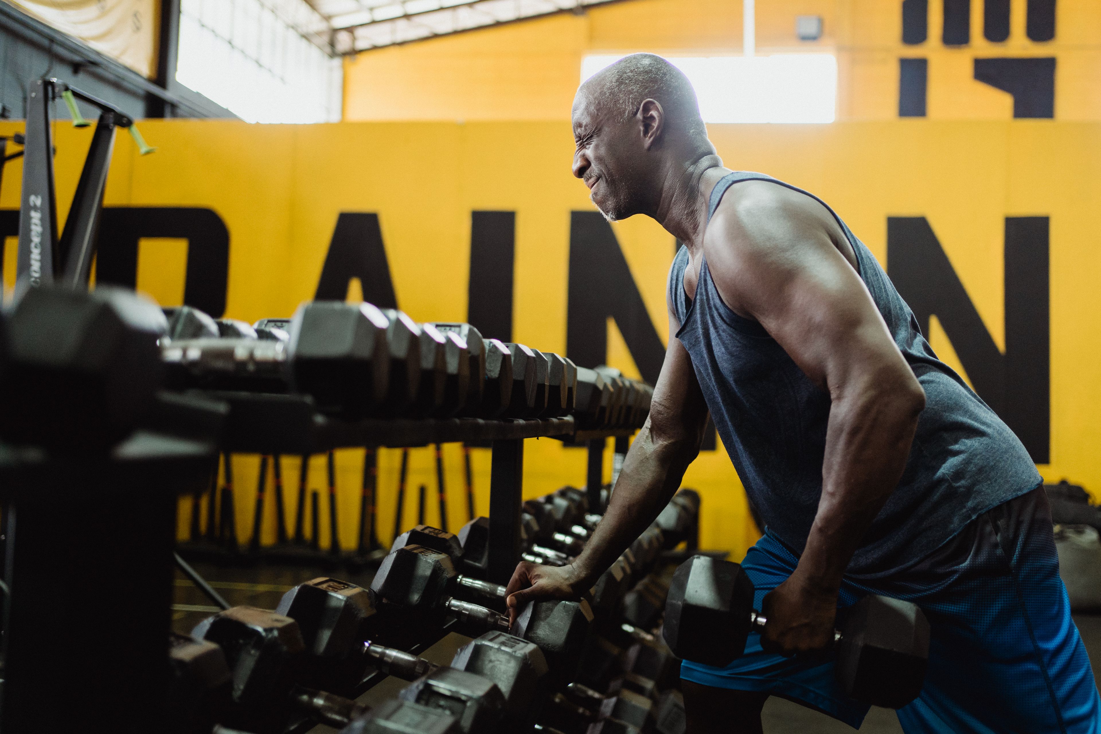 Man lifting dumbbells in gym focusing on strength training and fitness.