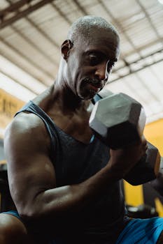 Focused senior man working out with a dumbbell in a gym setting, showcasing strength and dedication.