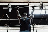 男子在健身房里从身后举起哑铃，彰显力量与健康