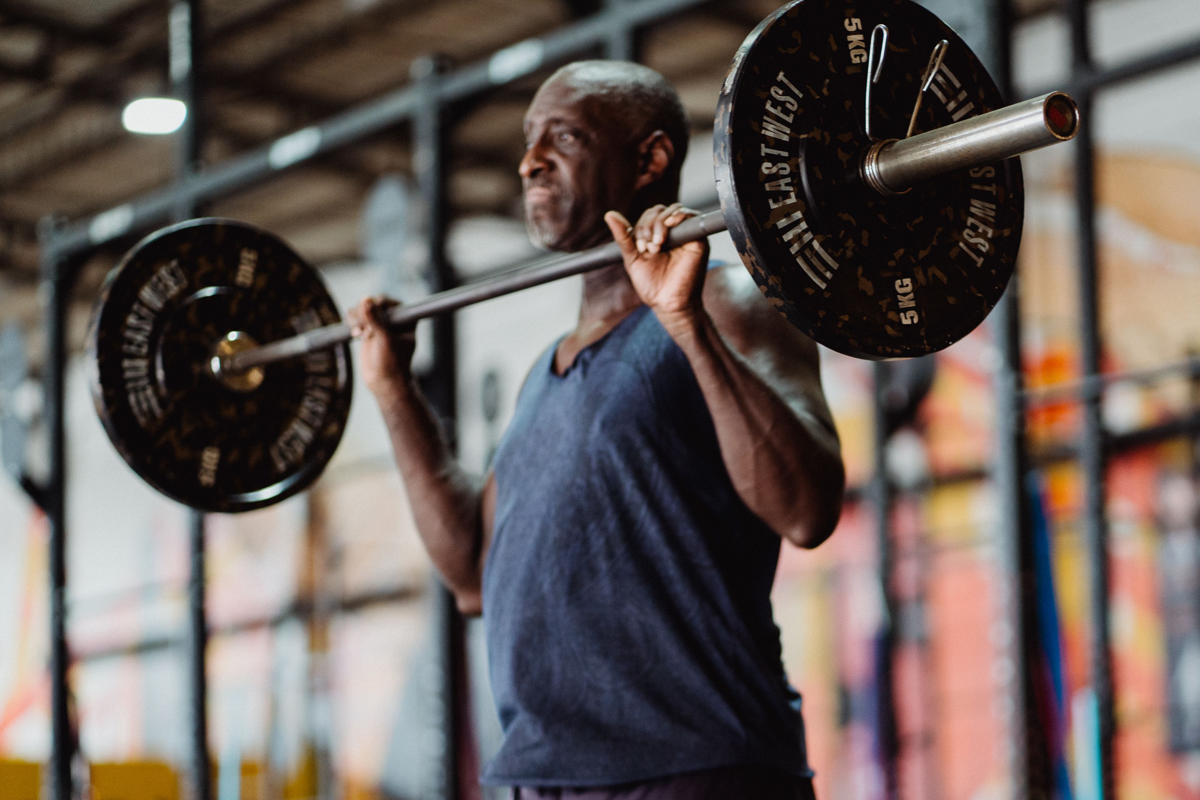 A focused man lifting weights in a gym setting, demonstrating strength and fitness.