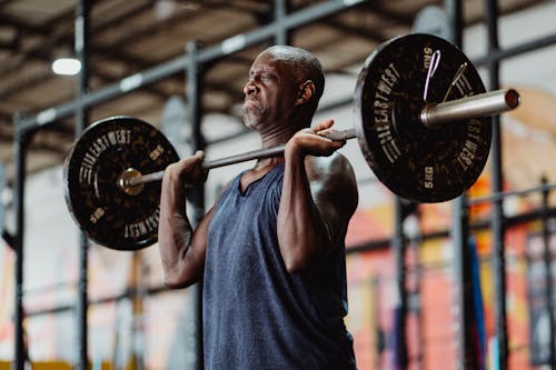Man in Blue Tank Top Lifting a Heavy Barbell