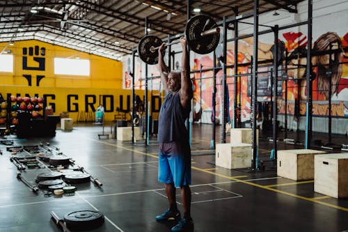 Man in Blue Tank Top Lifting a Heavy Barbell in the Gym